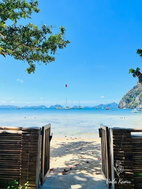 Open bamboo gate overlooking Corong Corong Beach, boats and limestone cliffs in El Nido
