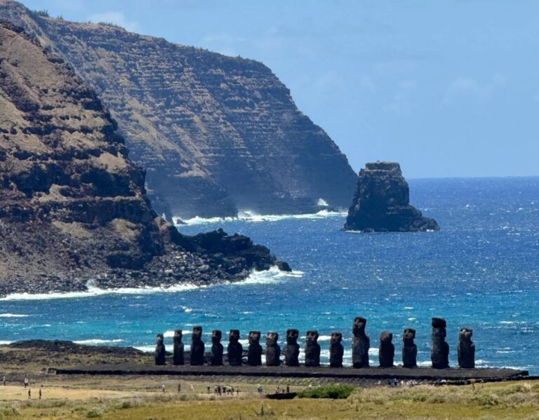 Moai lined up at Ahu Tongariki with blue ocean and volcanic cliffs behind them