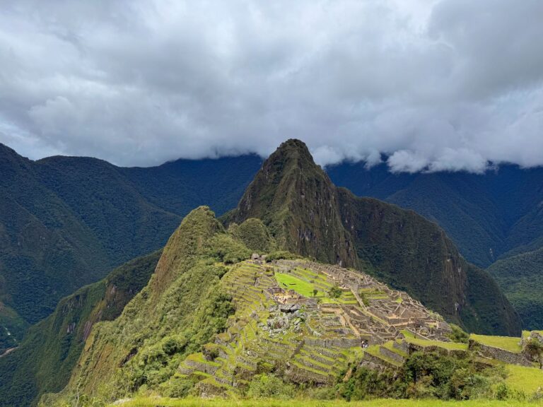 Stone buildings and green terraces at Machu Picchu beneath cloud-covered mountains