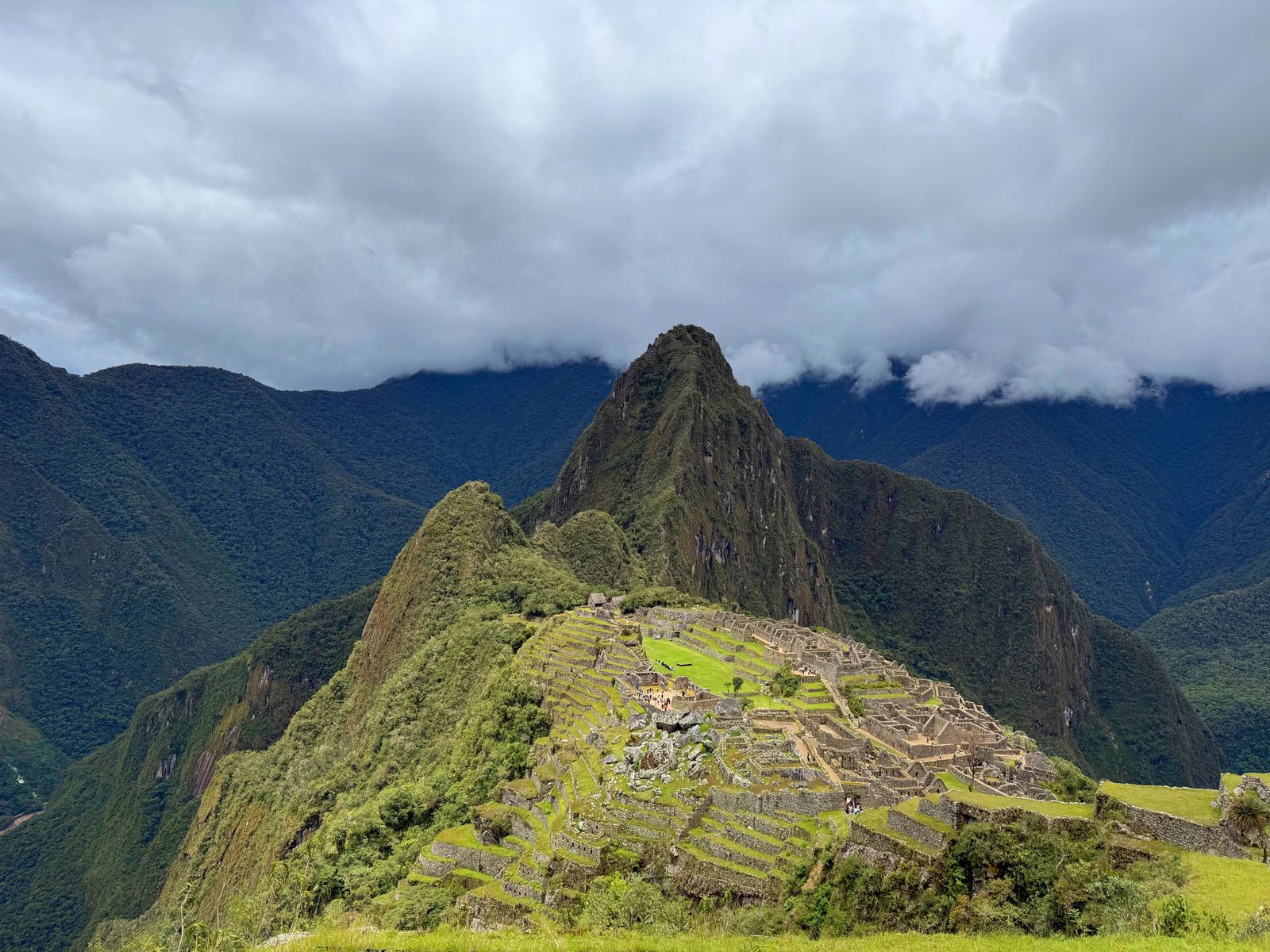 Stone buildings and green terraces at Machu Picchu beneath cloud-covered mountains