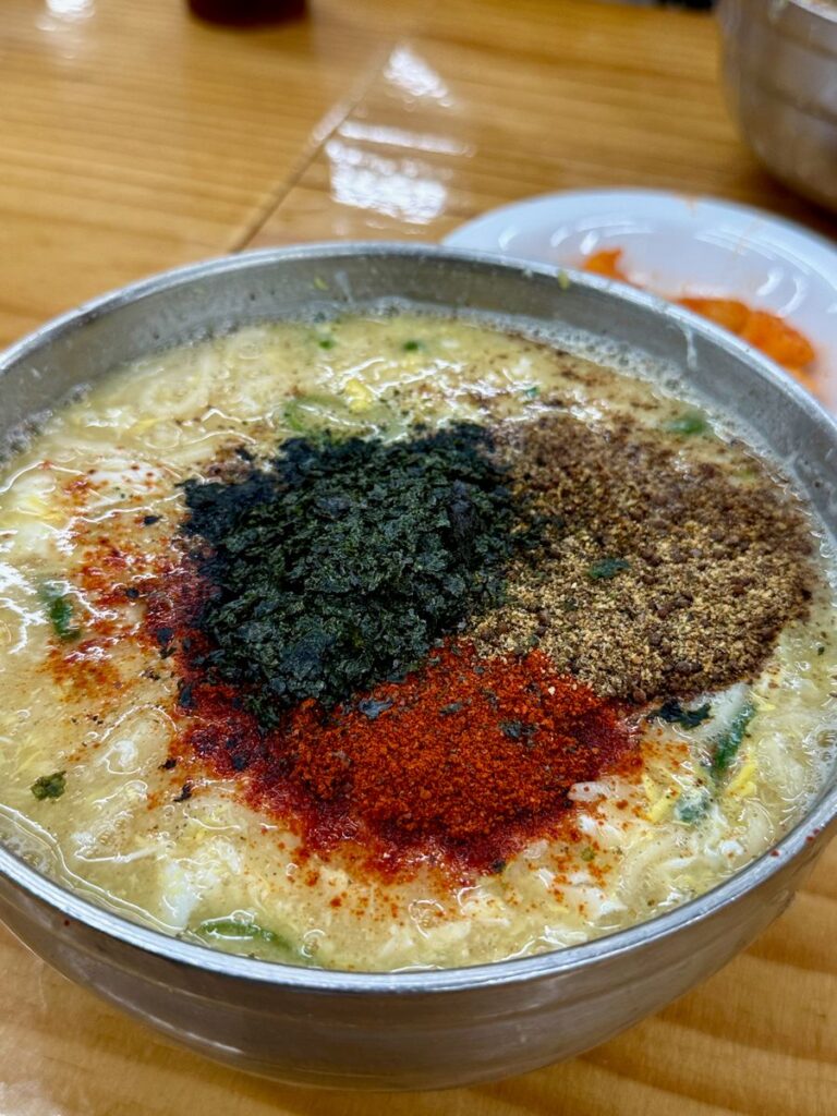 Knife-cut noodles at Veteran Kalguksu in Jeonju, topped with egg, seaweed and ground seeds