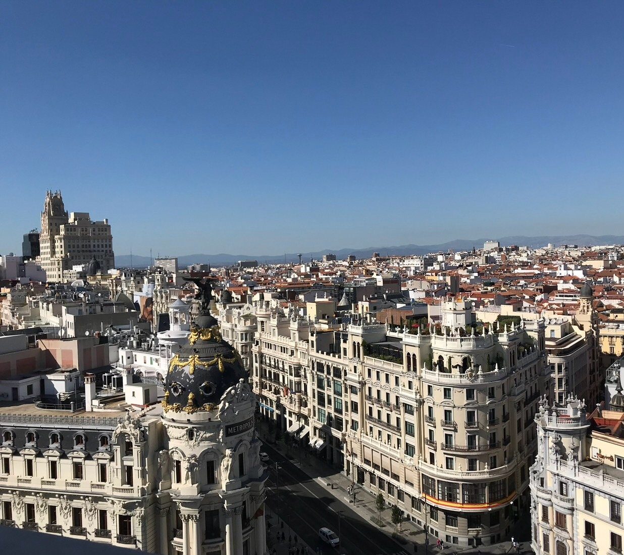 Madrid rooftops and the ornate black-and-gold dome of the Metropolis Building beneath a blue sky